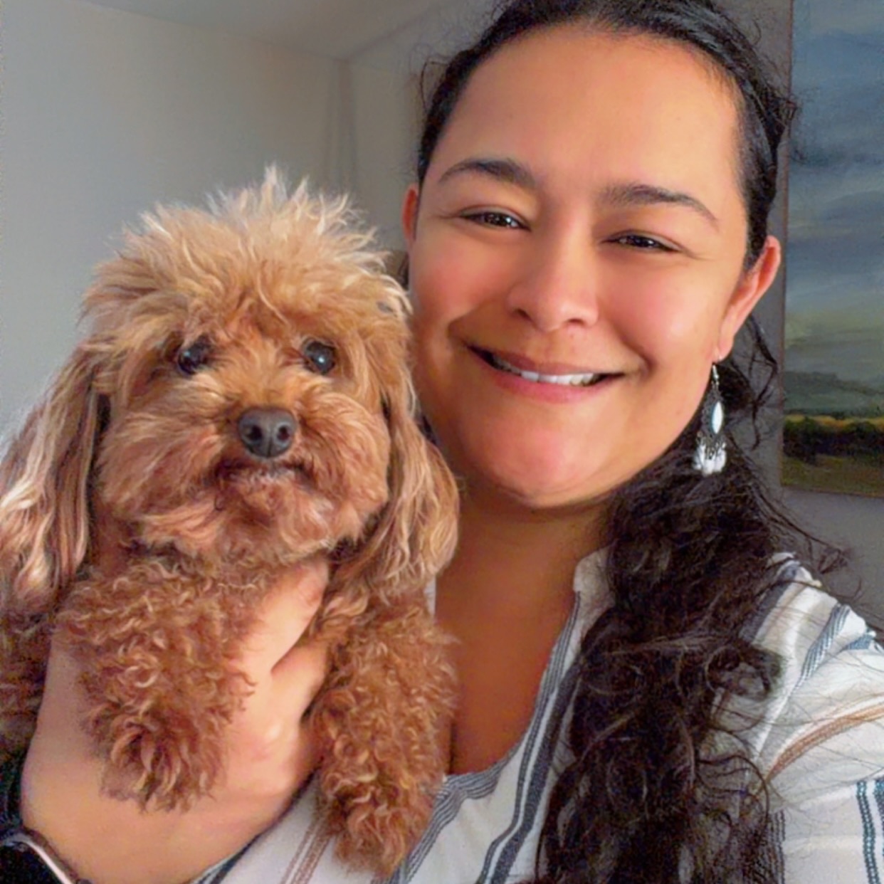 Woman holding a curly brown dog close for a portrait